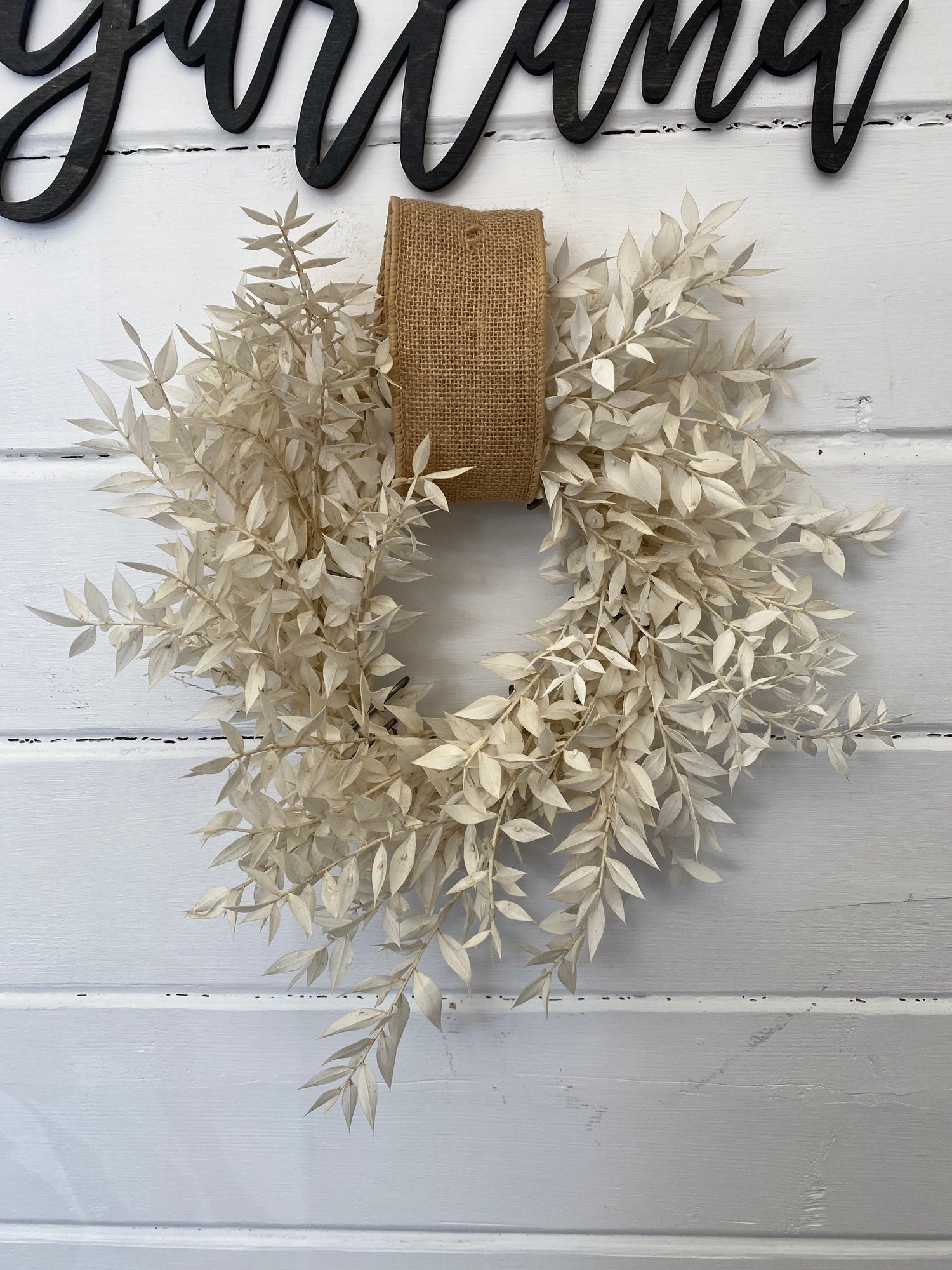 about elegant white wreath on ruscus wrapped easel from Walter